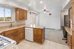 Kitchen with white appliances, kitchen peninsula, a textured ceiling, sink, and light colored carpet