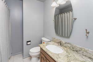 Bathroom featuring walk in shower, vanity, toilet, and tile patterned floors