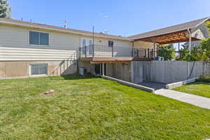 Rear view of property featuring central AC unit, a wooden deck, and a lawn