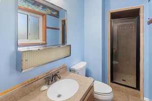 Bathroom with tile patterned flooring, vanity, toilet, and a shower with shower door