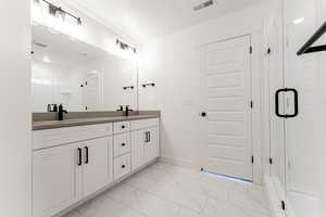 Bathroom featuring a textured ceiling, vanity, and a shower with door