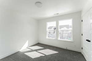 Empty room with plenty of natural light and dark colored carpet