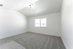 Carpeted empty room featuring vaulted ceiling and a textured ceiling