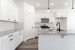 Kitchen with appliances with stainless steel finishes, decorative light fixtures, and white cabinetry