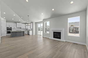 Unfurnished living room featuring light hardwood / wood-style floors, lofted ceiling, sink, and a wealth of natural light