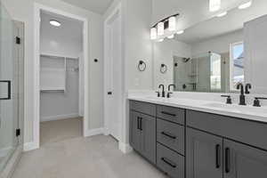 Bathroom featuring a shower with shower door and vanity