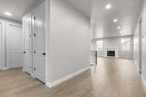 Hallway with a textured ceiling and light hardwood / wood-style flooring