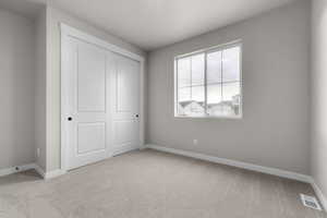 Unfurnished bedroom with light colored carpet and a closet