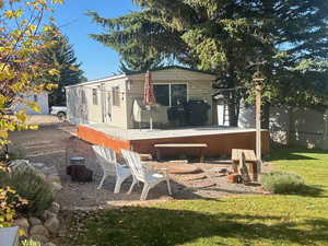 Back of house with a yard, a deck, and a fire pit