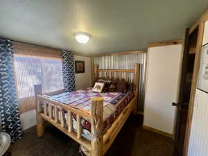 Bedroom with dark carpet and a textured ceiling