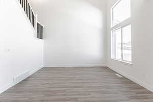 Empty room featuring a towering ceiling and light hardwood / wood-style flooring