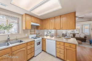 Kitchen with kitchen peninsula, ceiling fan, sink, and white appliances