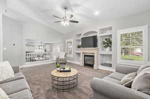 Carpeted living room featuring high vaulted ceiling, built in shelves, and ceiling fan