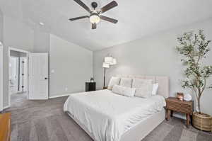 Carpeted bedroom featuring ceiling fan and vaulted ceiling