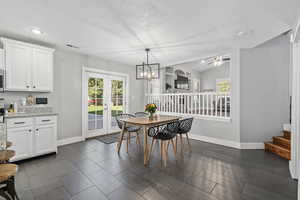 Dining space with french doors, ceiling fan with notable chandelier, a textured ceiling, and lofted ceiling