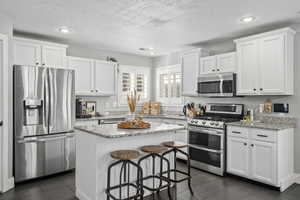 Kitchen featuring stainless steel appliances, white cabinetry, and a center island