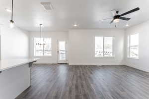 Interior space with a textured ceiling, dark hardwood / wood-style floors, and ceiling fan with notable chandelier