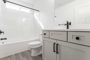 Full bathroom featuring vanity, hardwood / wood-style floors, shower / bathtub combination, and toilet