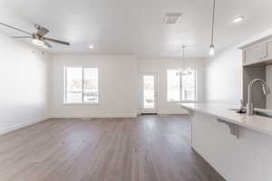 Kitchen featuring a breakfast bar, sink, pendant lighting, ceiling fan with notable chandelier, and light hardwood / wood-style floors