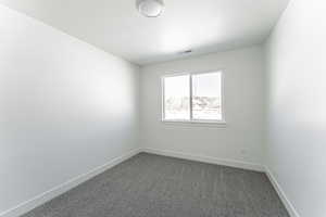 Unfurnished room with dark carpet and a textured ceiling