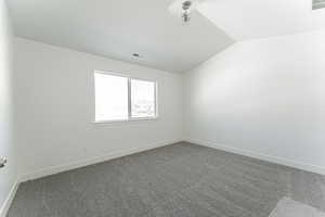 Carpeted spare room with lofted ceiling