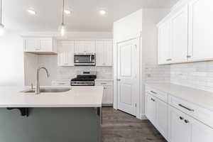 Kitchen featuring sink, white cabinetry, stainless steel appliances, and pendant lighting