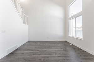 Empty room with dark wood-type flooring and a high ceiling