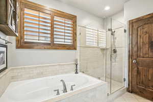 Bathroom with tile patterned flooring, separate shower and tub, and a healthy amount of sunlight