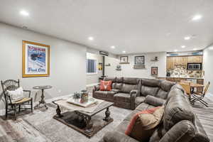 Living room with a textured ceiling and light hardwood / wood-style flooring