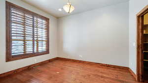 Empty room with a textured ceiling, hardwood / wood-style flooring, visible vents, and baseboards