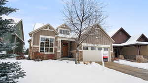 View of front of property featuring stone siding, board and batten siding, and an attached garage