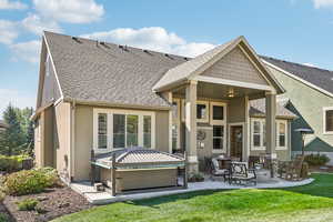 Rear view of house with cooling unit, a yard, and a hot tub