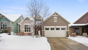 Craftsman-style home featuring a garage, stone siding, board and batten siding, and concrete driveway