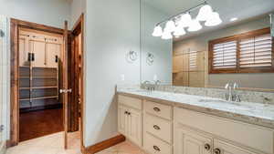 Bathroom with double vanity, a sink, a shower stall, and tile patterned floors