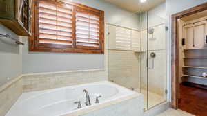 Bathroom featuring tile patterned flooring, a shower stall, and a bath