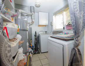 Washroom with light tile patterned floors, water heater, independent washer and dryer, and cabinets