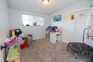 Recreation room with vaulted ceiling and light carpet