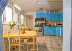 Kitchen with blue cabinets, stainless steel appliances, hanging light fixtures, and decorative backsplash