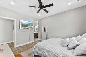 Bedroom with ceiling fan, connected bathroom, and wood-type flooring