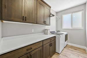 Laundry area with light wood-type flooring, separate washer and dryer, and cabinets