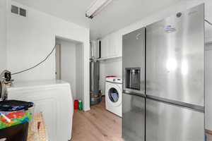 Clothes washing area featuring water heater, washer / clothes dryer, and light hardwood / wood-style flooring