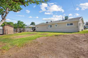 Back of house with a shed, a lawn, and central AC