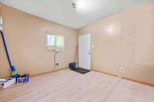 Spare room with light wood-type flooring and lofted ceiling