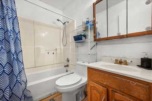 Full bathroom featuring wood-type flooring, vanity, toilet, and shower / bathtub combination with curtain