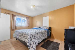 Bedroom with light hardwood / wood-style flooring and a textured ceiling