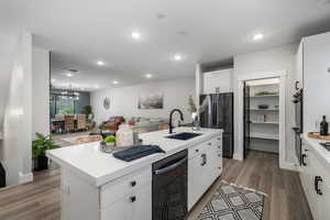 Kitchen featuring sink, a center island with sink, white cabinetry, stainless steel appliances, and dark hardwood / wood-style flooring