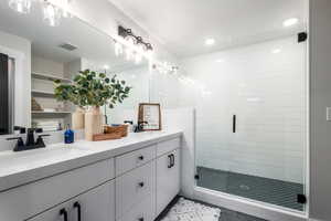 Bathroom featuring vanity, a shower with shower door, and tile patterned floors