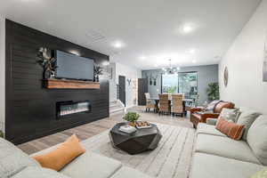 Living room featuring an inviting chandelier, a fireplace, and light hardwood / wood-style floors