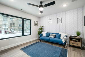 Living room with tile walls, ceiling fan, and hardwood / wood-style floors