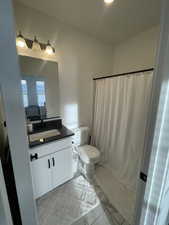 Main floor Bathroom with walk in shower, vanity, and toilet